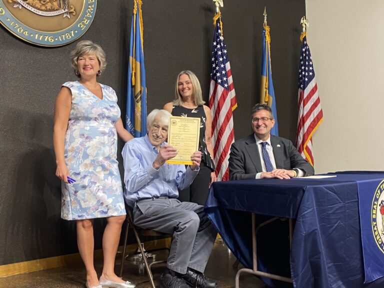Sen. Laura Sturgeon, retired Rep. John Kowalko Jr., Rep. Cyndie Romer, and Governor Matt Meyer pose with signed copy of SB 4